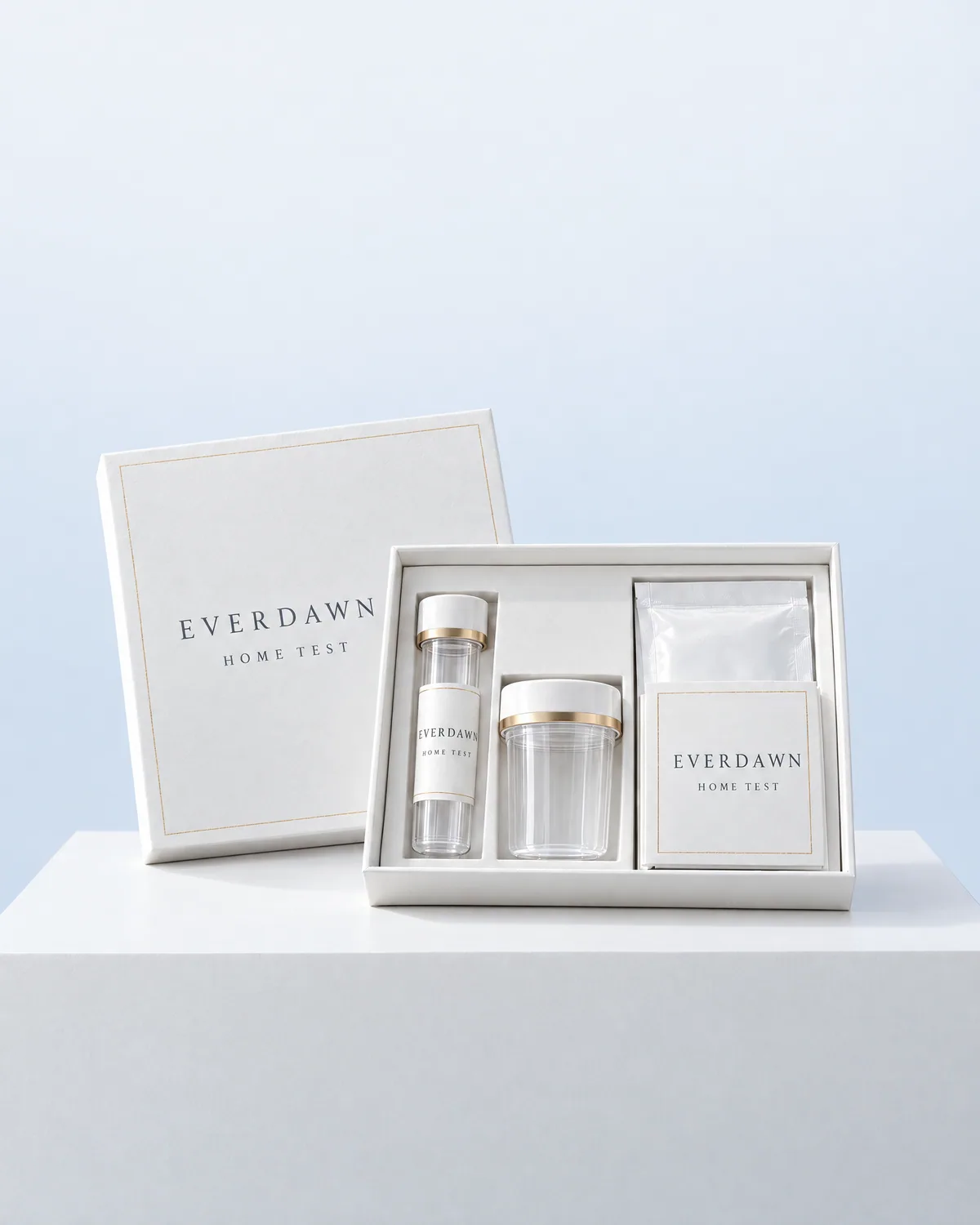 An Everdawn at-home test kit with a sample tube, a specimen cup and a sealed pouch, on a white plinth in a pale blue studio.
