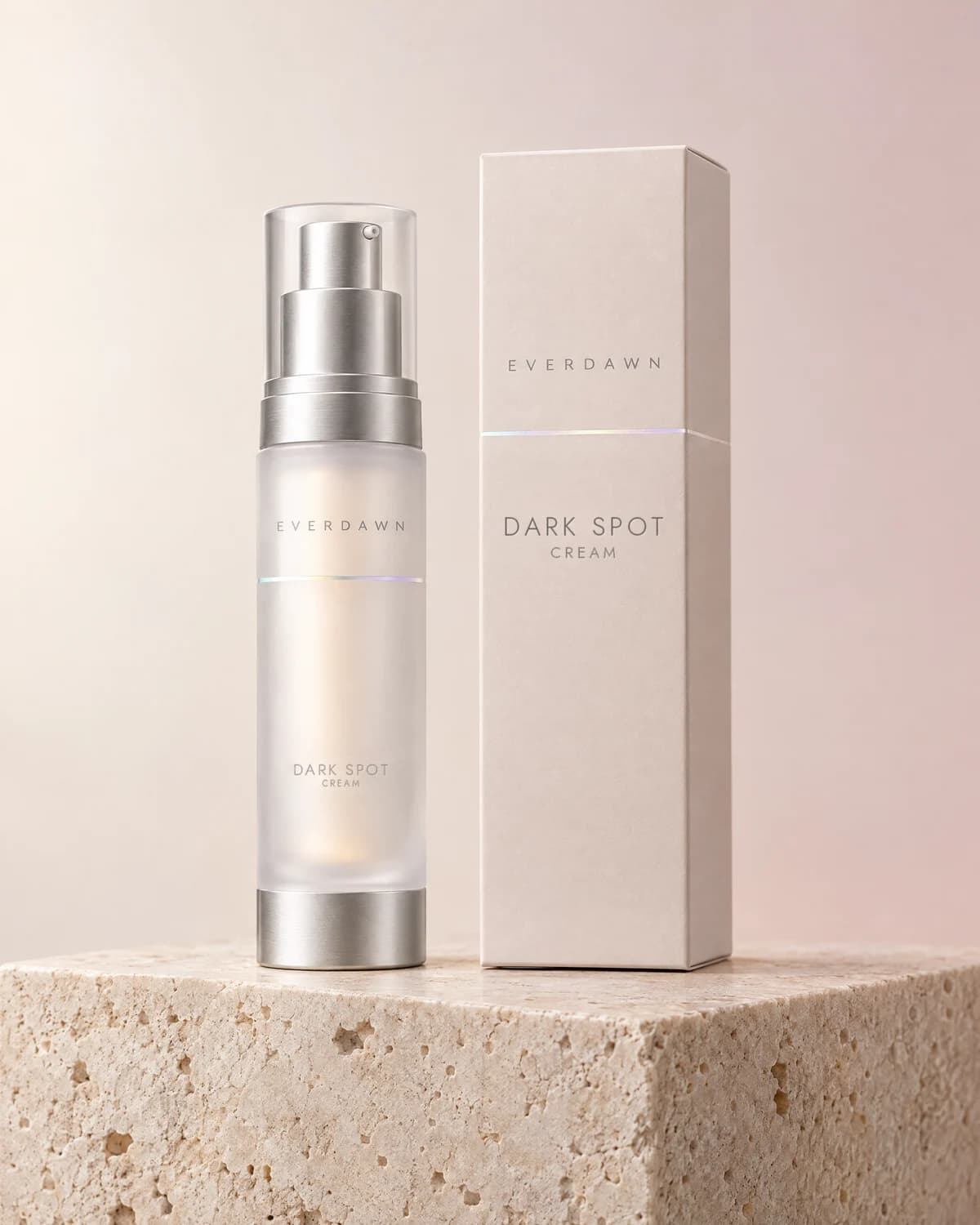 Illustrative packaging: a dark spot cream airless pump beside its carton on a travertine plinth against a soft studio background. Your medicine is labeled and dispensed by the licensed pharmacy.