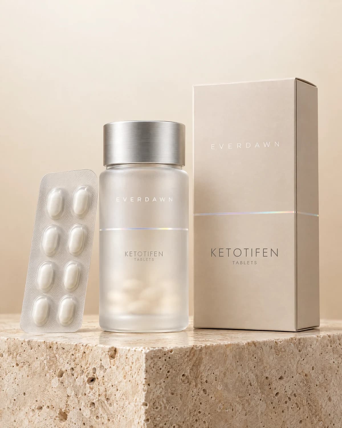 Illustrative packaging: a ketotifen tablet bottle with its carton and a blister card on a travertine plinth against a soft studio background. Your medicine is labeled and dispensed by the licensed pharmacy.