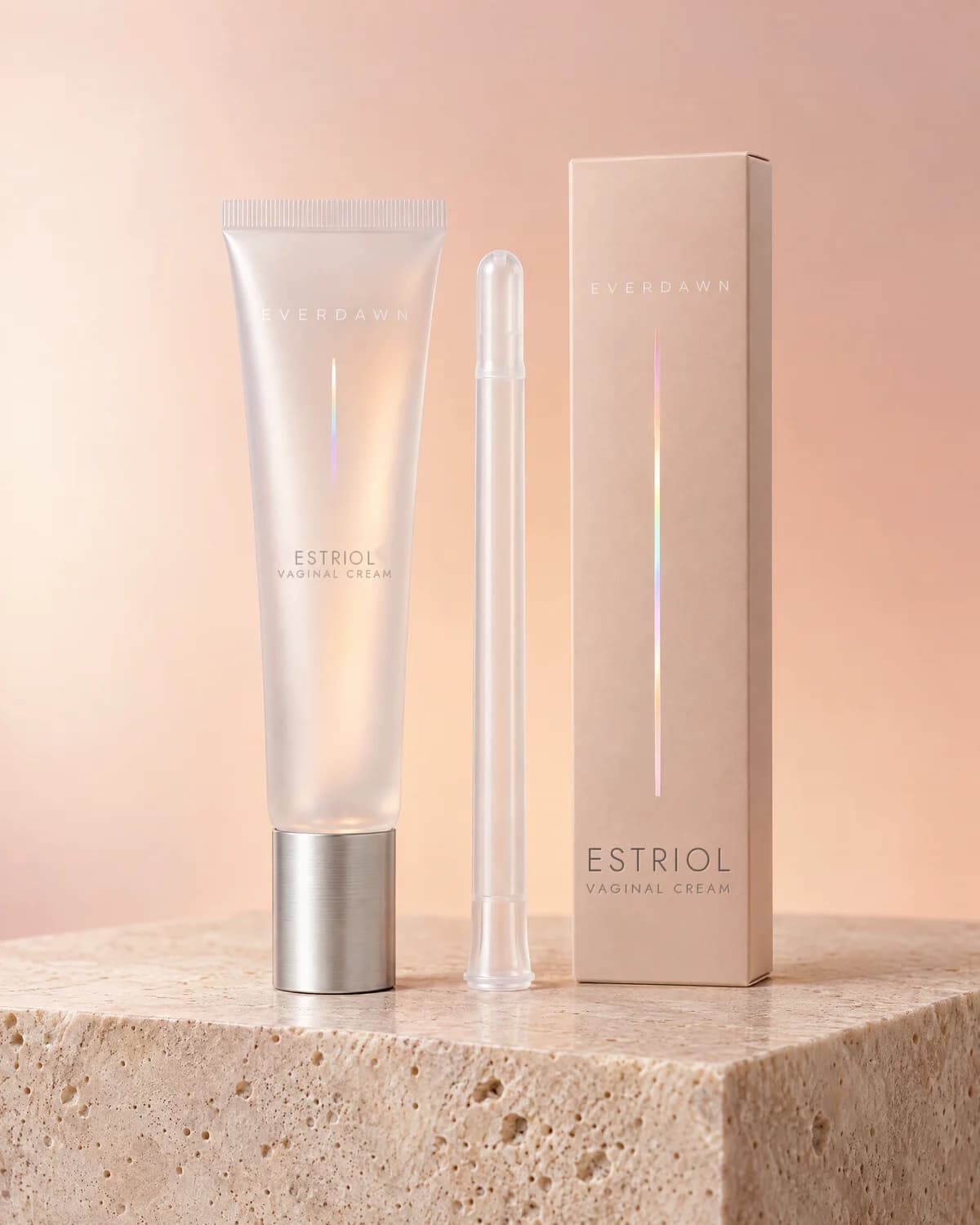 Illustrative packaging: an estriol vaginal cream tube with its applicator beside its carton on a travertine plinth against a soft studio background. Your medicine is labeled and dispensed by the licensed pharmacy.
